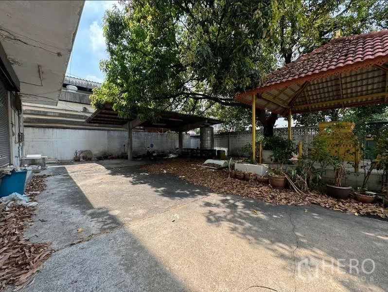 Home Office for sale in Bang Na, Bangkok - Shaded yard with mature tree, small pavilions and covered parking bays.