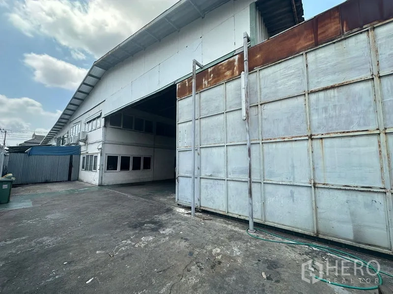 Warehouse for rent in Suan Luang, Bangkok - Industrial warehouse exterior with large sliding metal gate and wide loading yard.