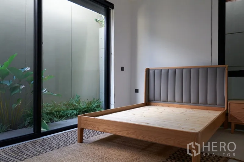 บ้าน ให้เช่าในWatthana, Bangkok - ห้องนอนชั้นล่าง เปิดสู่สวนผ่านประตูกระจก เตียงไม้