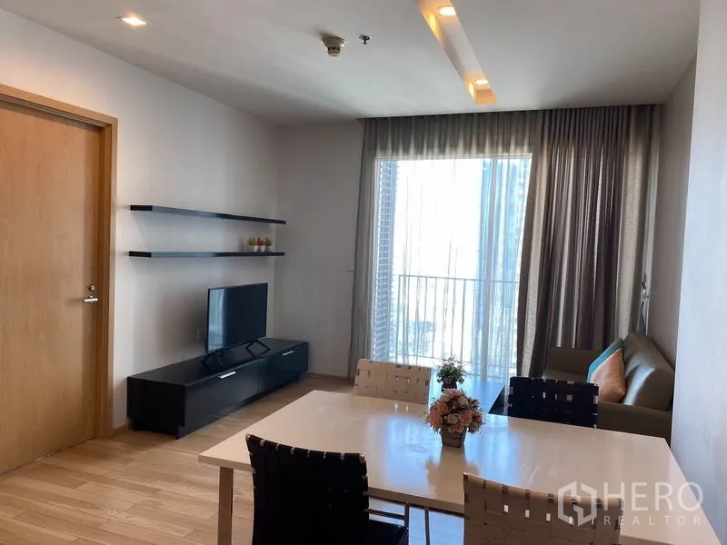 คอนโด ให้เช่าในKhlong Toei, Bangkok - พื้นที่ทานอาหาร 4 ที่นั่ง ใกล้ระเบียงและชั้นวางทีวี ผ้าม่านโปร่งสวย