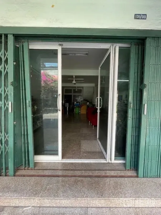 Shophouse for sale in Sathon, Bangkok - Ground-floor shopfront with green folding security gate and sliding glass doors opening to the interior.