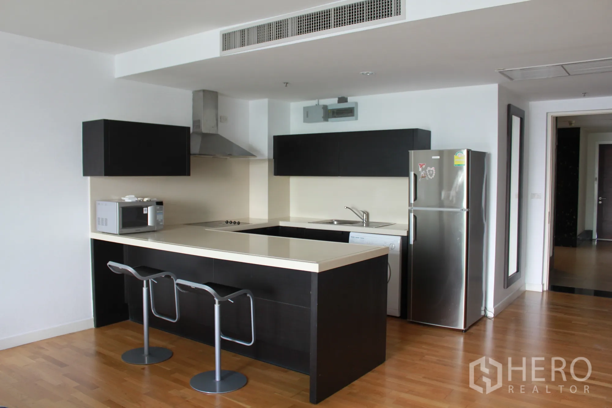 公寓 出租在Sathon, Bangkok - U 型厨房，早餐中岛，灶台、油烟机、微波炉与不锈钢冰箱。