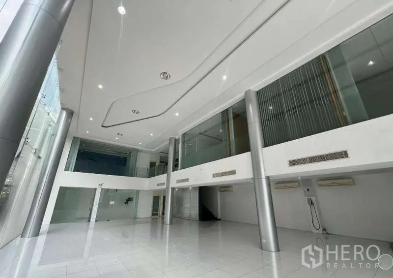 展厅 出租 - 大面积展示空间，白色地面、高柱与夹层走道。