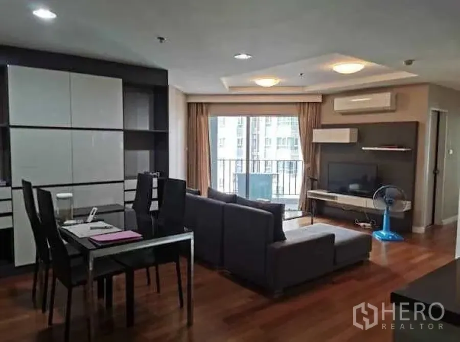 Condominium for rent in Huai Khwang, Bangkok - Open-plan living and dining room with balcony access, TV wall unit and city-facing sliding doors.