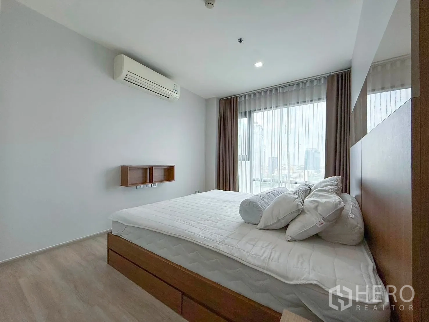 Condominium for rent in Khlong Toei, Bangkok - Bedroom showing air-conditioner, wide window, and floating shelves.