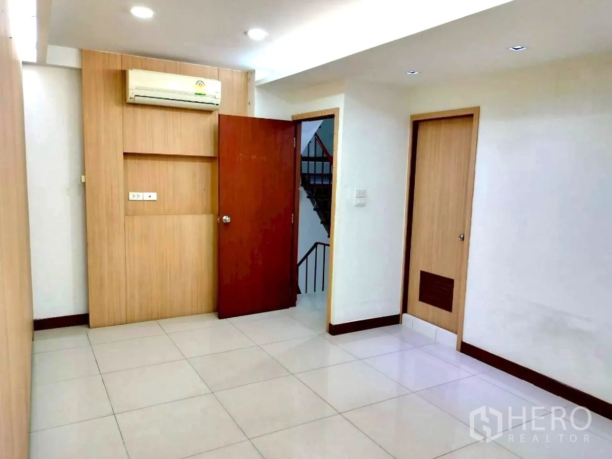 Home Office for rent in Watthana, Bangkok - Compact room with tiled floors, built-in wood paneling, downlights, and air conditioner.