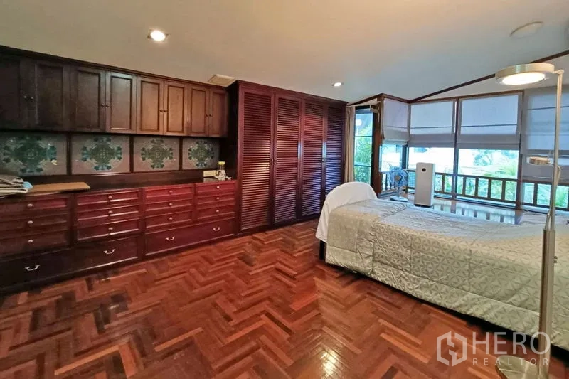 公寓 出售在Bangkok - 卧室铺人字拼木地板，整排深色木柜收纳充足。