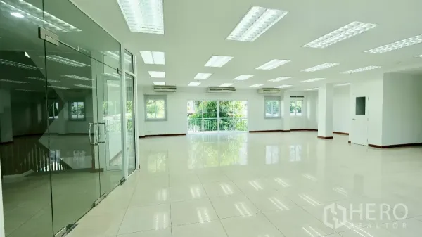 Office Space for rent - Open workspace with glass partition entry, glossy tile flooring, LED lights, and green views.
