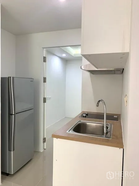 คอนโด ให้เช่าหรือขายในKhlong Toei, Bangkok - ครัวขนาดกะทัดรัดพร้อมอ่างล้างสแตนเลส เครื่องดูดควัน และตู้เย็นสีเงิน
