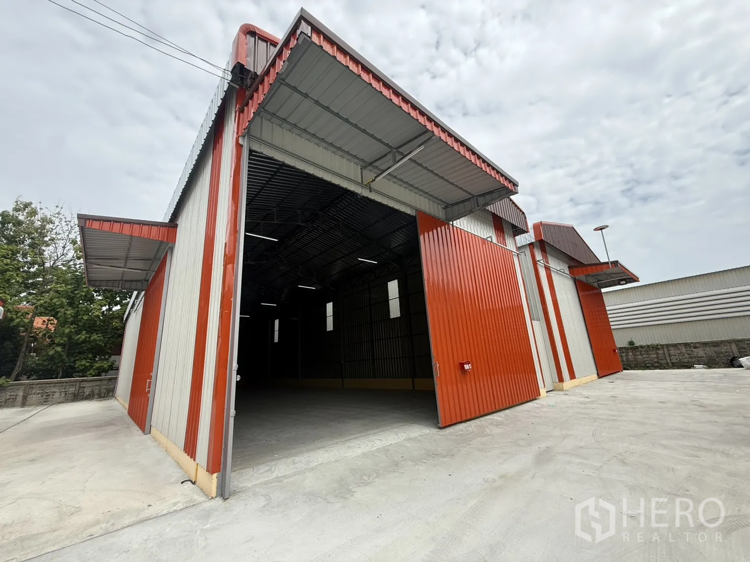 Warehouse for rent in Wang Thonglang, Bangkok - Warehouse exterior with large sliding entrance door open and concrete loading apron.