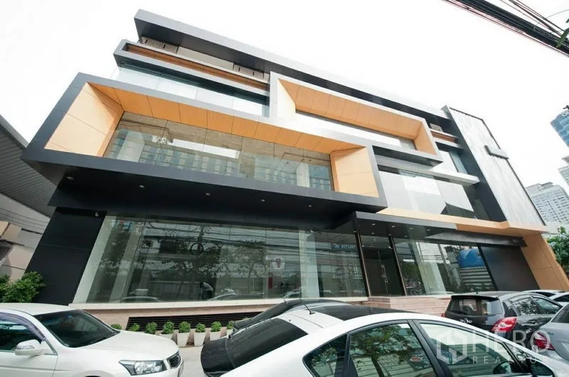 零售空间 出租在Bangkok - 曼谷乍都节区现代商业大楼外观，整面玻璃立面与现场停车位。