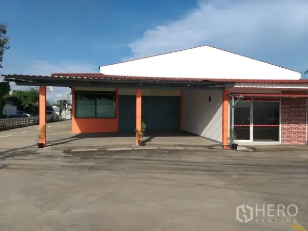 货栈 出租在Khlong Sam Wa, Bangkok - 主立面配卷帘门和玻璃接待区，前方大面积硬地。