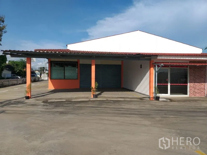 货栈 出租在Khlong Sam Wa, Bangkok - 主立面配卷帘门和玻璃接待区，前方大面积硬地。