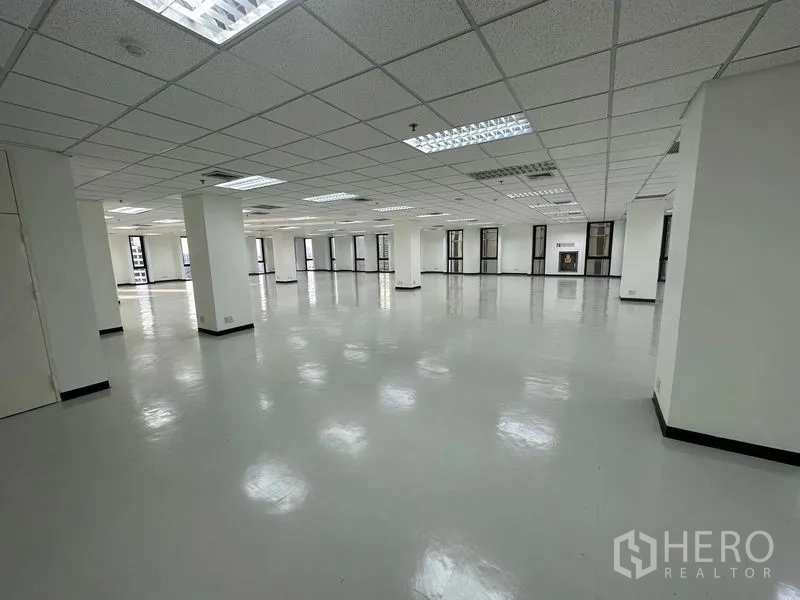 Office Space for rent - Bright vacant office space with glossy flooring, multiple pillars, and perimeter windows for natural light.