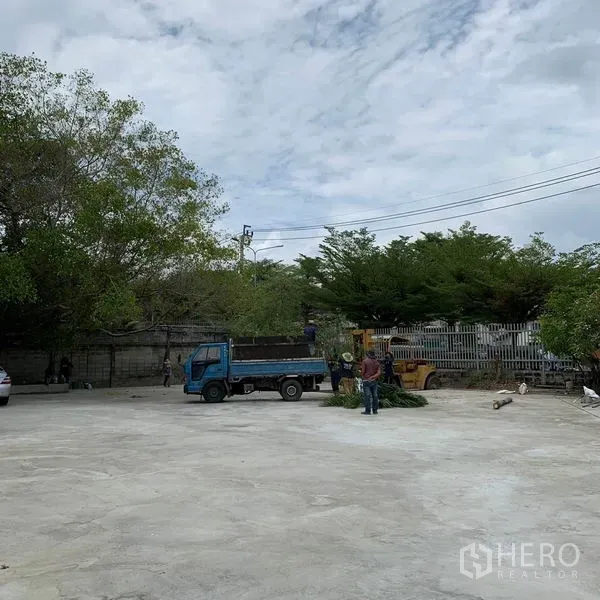 Warehouse for rent in Yan Nawa, Bangkok - Large open concrete yard with boundary fence and trees, suitable for truck maneuvering.