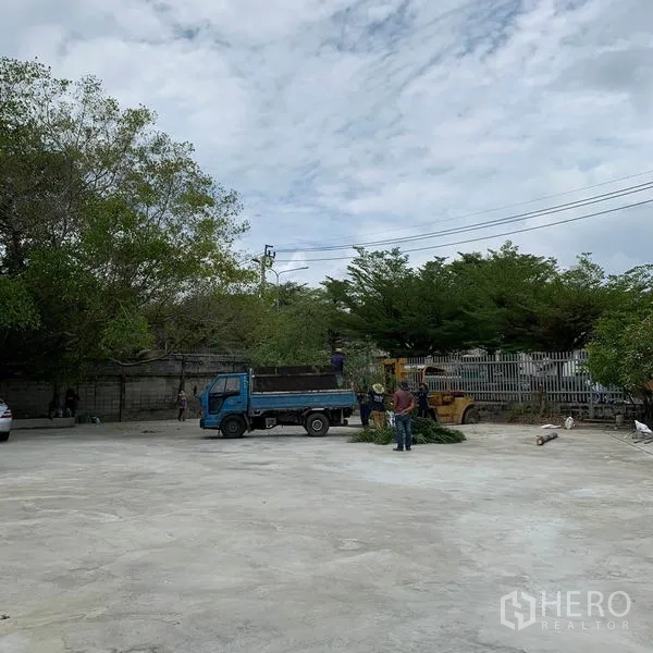 Warehouse for rent in Yan Nawa, Bangkok - Large open concrete yard with boundary fence and trees, suitable for truck maneuvering.