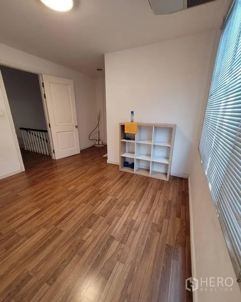 联排别墅 出售在Bang Kapi, Bangkok - 明亮的多功能房，木地板、百叶窗与格子书架。