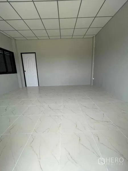 Warehouse for rent in Phra Samut Chedi, Samut Prakan - Tiled office room with grid ceiling, painted walls, and aluminum windows and door.
