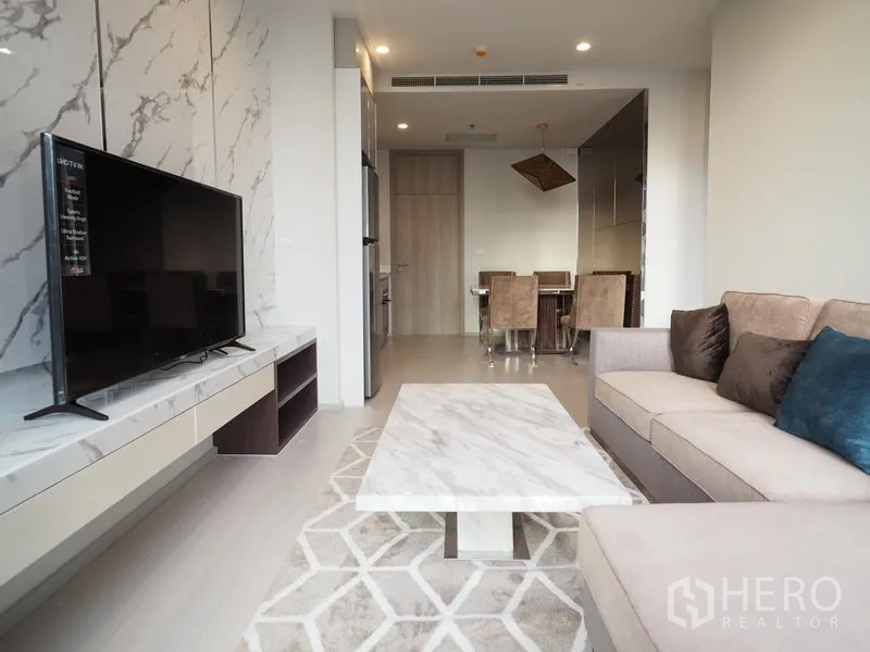 Condominium for rent in Pathum Wan, Bangkok - Open-plan living and dining area with marble coffee table, TV console and beige sofa.