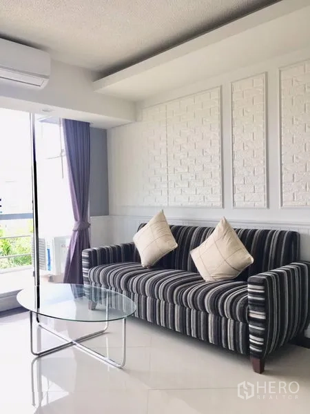 คอนโด ให้เช่าในKhlong Toei, Bangkok - มุมนั่งเล่นสบาย โซฟาลายทาง โต๊ะกลางกระจก และผนังลายอิฐตกแต่ง