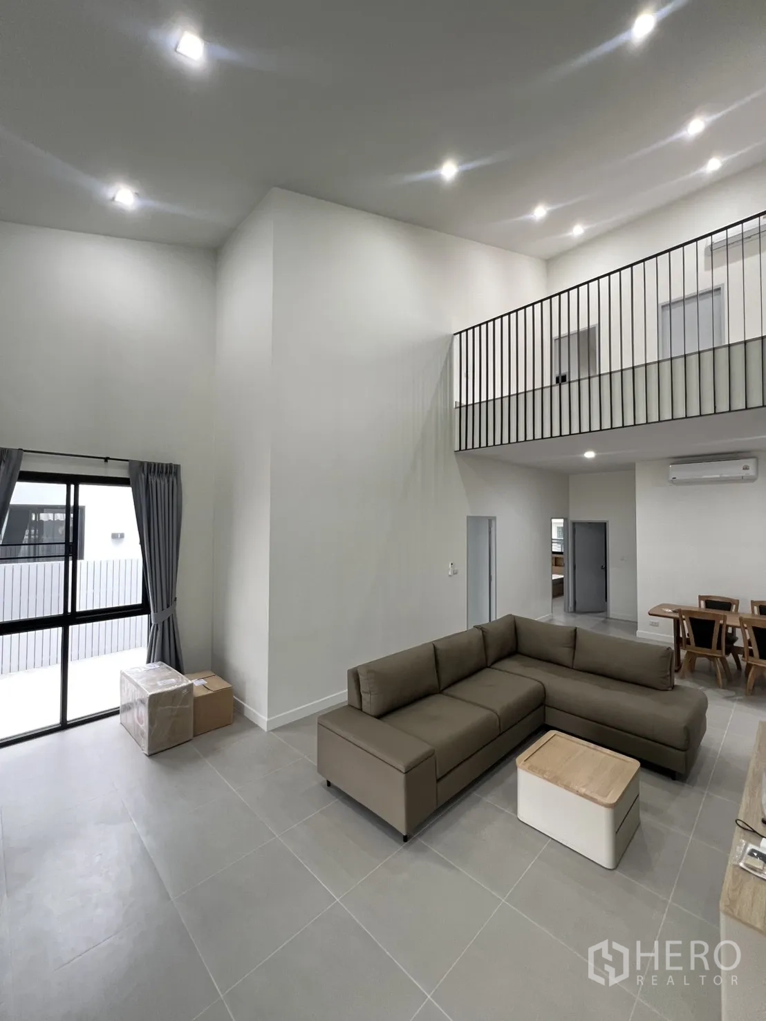 Detached House for rent in Saphan Sung, Bangkok - L-shaped sofa facing TV unit beneath high ceiling near dining area.
