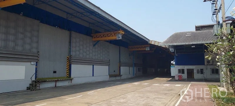 工厂 出租在Phra Pradaeng, Samut Prakan - 两栋仓库间的车道，带月台雨篷与人行斑马线。