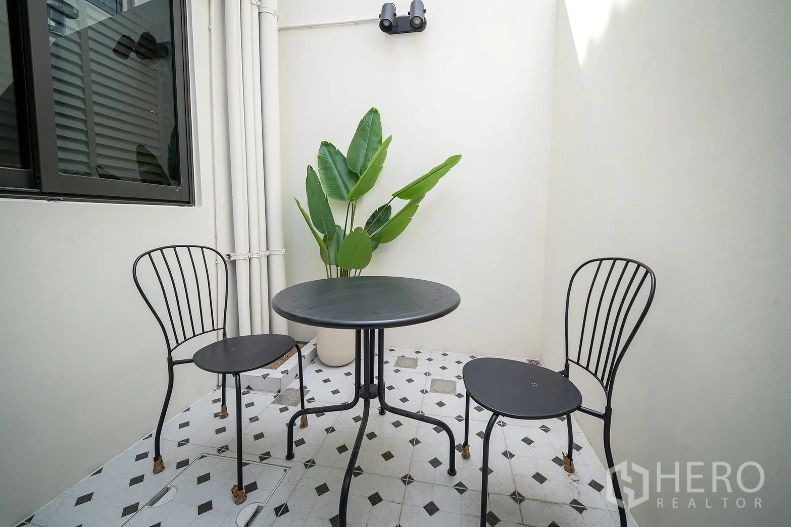 联排别墅 for rent in Bang Phli, Samut Prakan - 阳光私密露台，圆桌、两把椅子与热带盆栽。