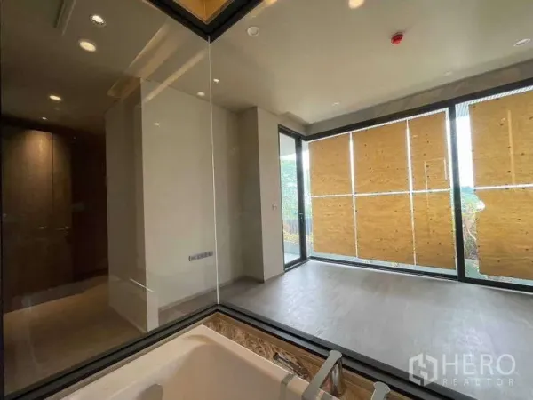 คอนโด ขายในPhaya Thai, Bangkok - อ่างอาบน้ำข้างผนังกระจก มองไปยังห้องนอนที่มีประตูกระจกบานเลื่อนและมู่ลี่