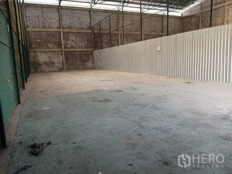 Warehouse for rent in Prawet, Bangkok - Spacious warehouse interior with high steel roof, concrete floor, and corrugated metal wall.