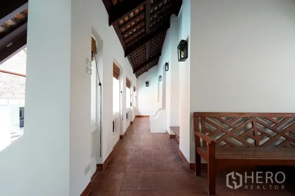 บ้าน ให้เช่าในWatthana, Bangkok - ทางเดินคลุมหลังคาพร้อมไฟติดผนังสไตล์โคมและม้านั่งไม้ มองเห็นโซนสระว่ายน้ำ