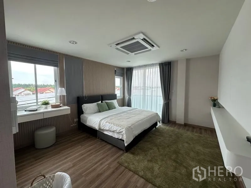 货栈 出售在Pathum Thani - 宽敞主卧，大片窗户、绿色地毯与吊顶嵌入式空调。