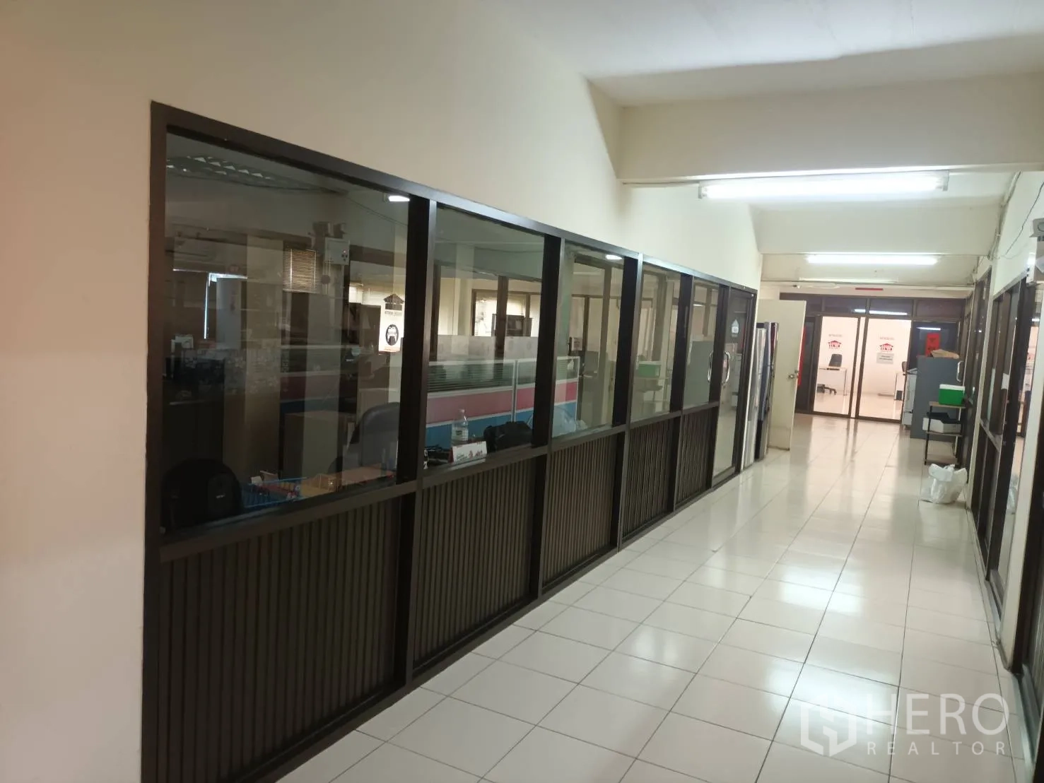 Warehouse for rent in Bang Phli, Samut Prakan - Open-plan office area with workstations behind a sliding glass door and tiled flooring.