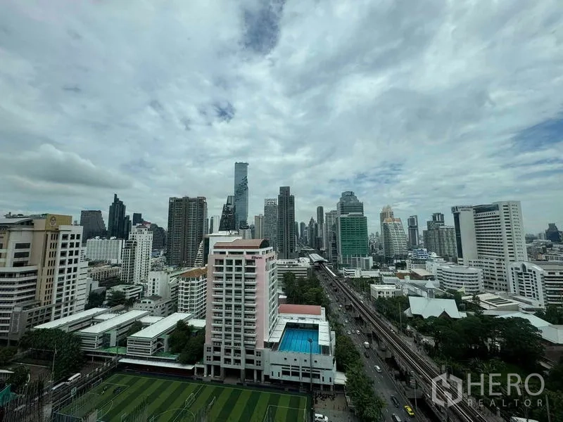 Condominium for sale in Bang Rak, Bangkok - Panoramic city skyline with BTS tracks, sports field and swimming pool from high floor.