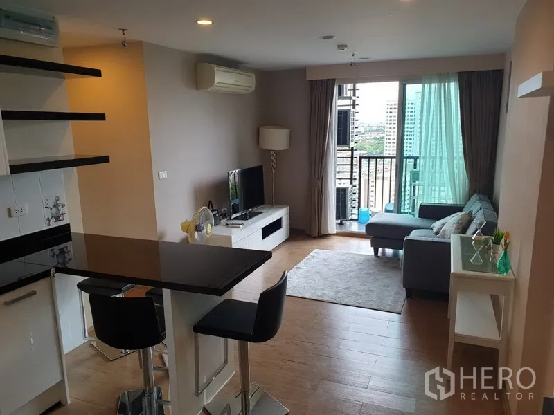 Condominium for rent in Watthana, Bangkok - Bright living area leading to a balcony with city view beside the dining bar.