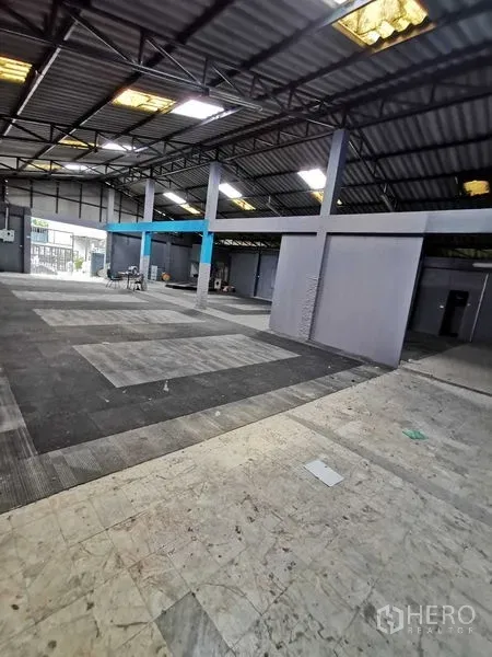 货栈 出租在Nonthaburi - 开放式仓库内部，钢桁架屋顶、采光窗与灰色隔间。