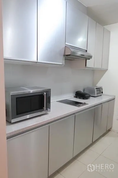 คอนโด ให้เช่าในKhlong Toei, Bangkok - ครัวแบบกัลเลย์ ตู้สีเมทัลลิก เตาไฟฟ้า เครื่องดูดควัน ไมโครเวฟ และเครื่องปิ้งขนมปัง