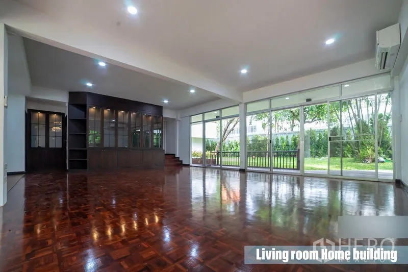Detached House for rent in Khlong Toei, Bangkok - Spacious living room featuring a dark wood built‑in cabinet, glass walls and garden view.