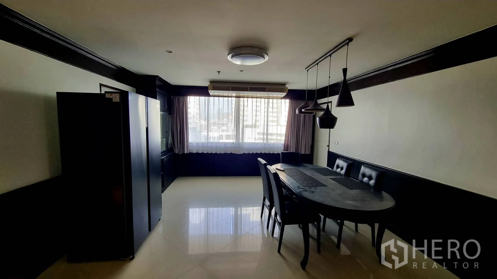 公寓 出租在Watthana, Bangkok - 明亮餐区，吊灯与大窗，旁有双门冰箱。