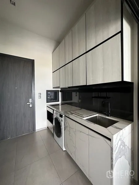 คอนโด ให้เช่าในPhra Khanong, Bangkok - ครัวทางเดินพร้อมตู้เก็บของเหนือศีรษะ เคาน์เตอร์หิน ซิงก์ และเครื่องใช้ไฟฟ้า