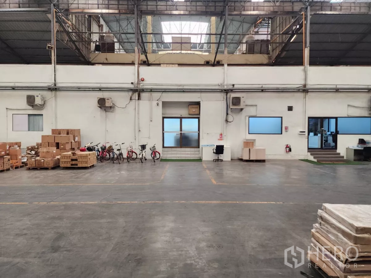 工厂 出租在Mueang Samut Sakhon, Samut Sakhon - 仓库墙面设办公室、装卸门与堆放箱件。