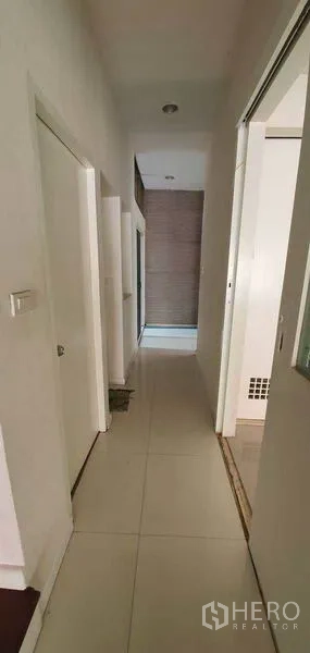 Home Office for rent in Watthana, Bangkok - Bright hallway with white tiled floor and multiple interior doors.