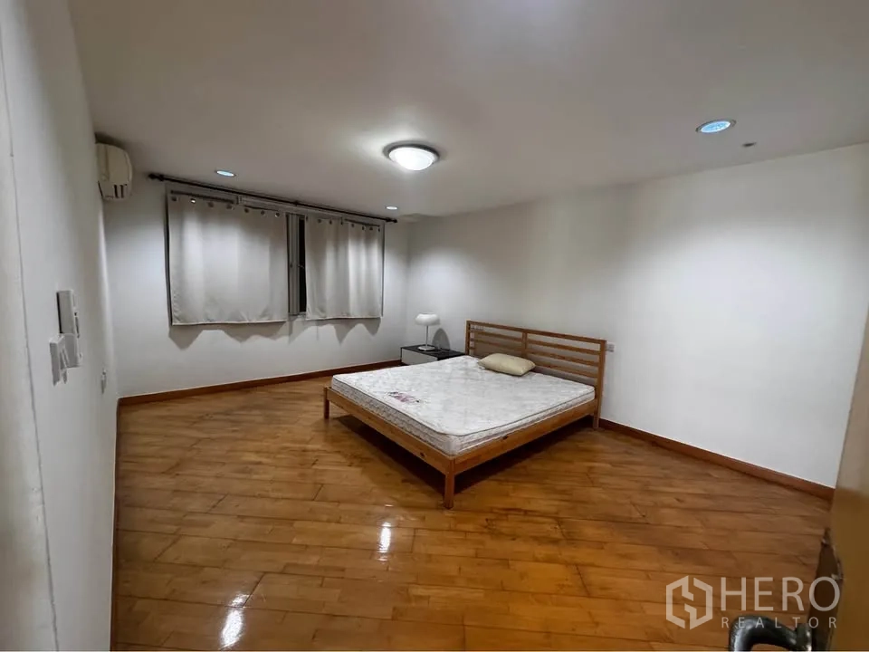 ทาวน์เฮาส์ for rent in Huai Khwang, Bangkok - ห้องนอนเรียบง่ายพร้อมเตียง โต๊ะข้าง และพื้นไม้เงางาม.
