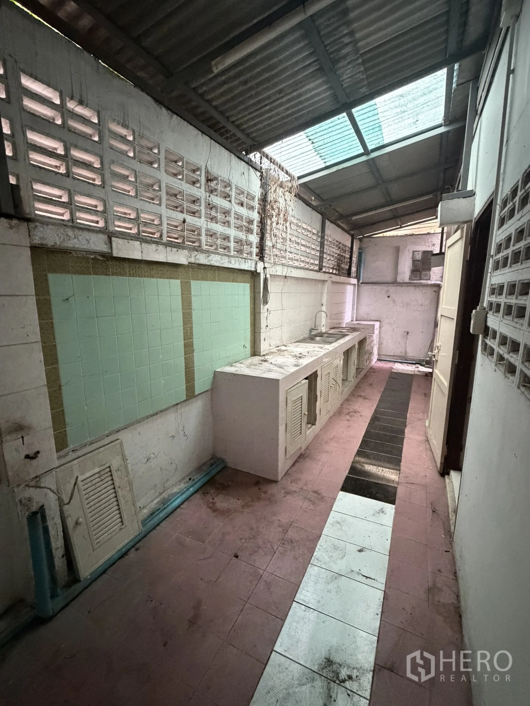 Shophouse for rent in Sathon, Bangkok - Narrow service kitchen with a long concrete counter and skylight roof.