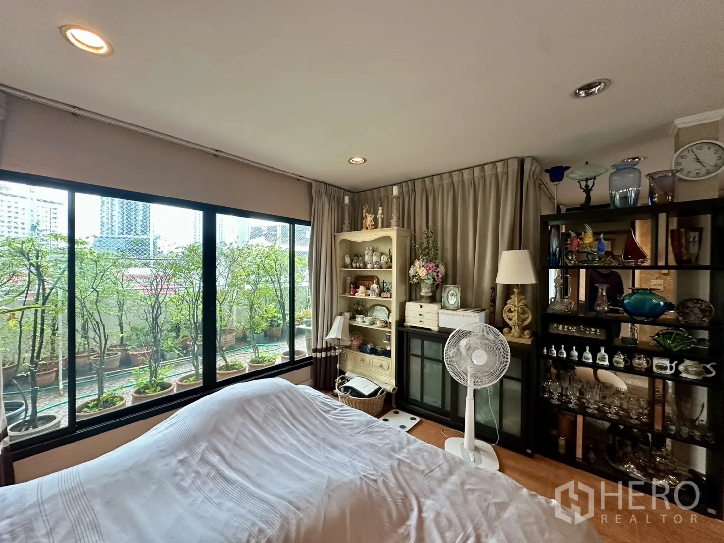 Shophouse for sale in Watthana, Bangkok - Bedroom with large windows to the terrace and shelving with glassware.
