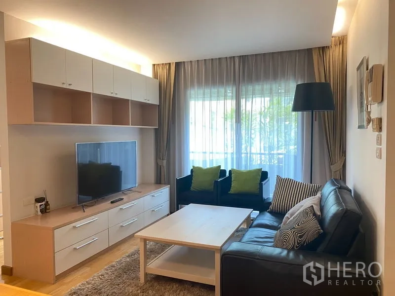 คอนโด ให้เช่าหรือขายในKhlong Toei, Bangkok - ห้องนั่งเล่นสว่างพร้อมตู้ทีวี โซฟาหนัง และผ้าม่านโปร่งที่เปิดสู่ระเบียง