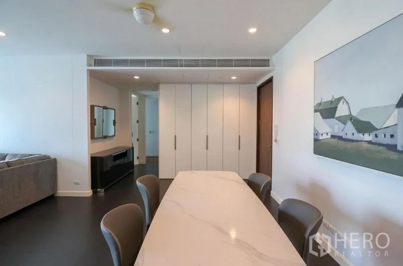 Condominium for rent in Pathum Wan, Bangkok - Dining area with a marble-top table, built-in storage and recessed lighting.