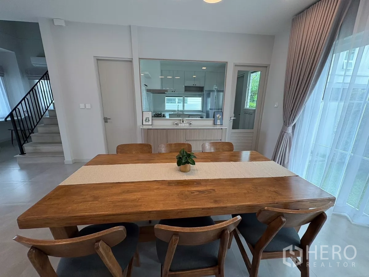 Detached House for rent or sale in Bang Phli, Samut Prakan - Solid wood dining table for six beside the kitchen pass-through window.