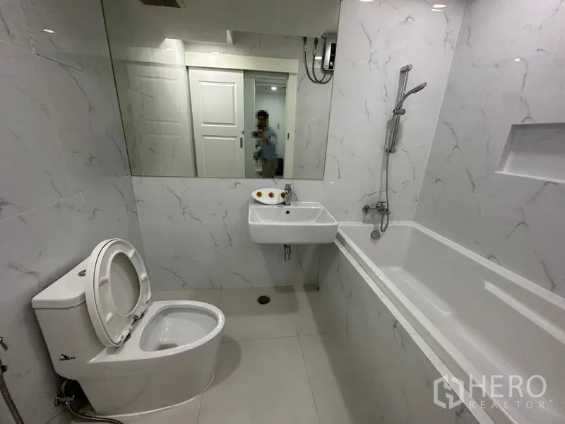 คอนโด ให้เช่าในWatthana, Bangkok - ห้องน้ำพร้อมอ่างอาบน้ำ ชาวเวอร์แบบสายฝักบัว กระจกเงาบานใหญ่ และผนังสีขาวลายหินอ่อน