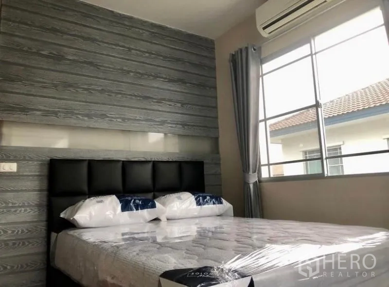 Detached House for rent in Prawet, Bangkok - Bedroom with textured accent wall, bed, air-conditioning and window.