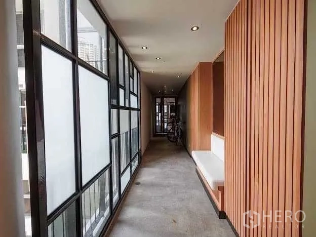 Condominium for sale in Yan Nawa, Bangkok - Private internal corridor with frosted glass panels, wood slat walls and built‑in bench seating.